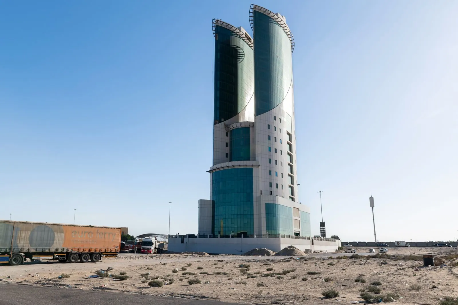 البرج من خلف أرض مفتوحة، وفي المقدمة شاحنة ومقطورات متوقفة.
