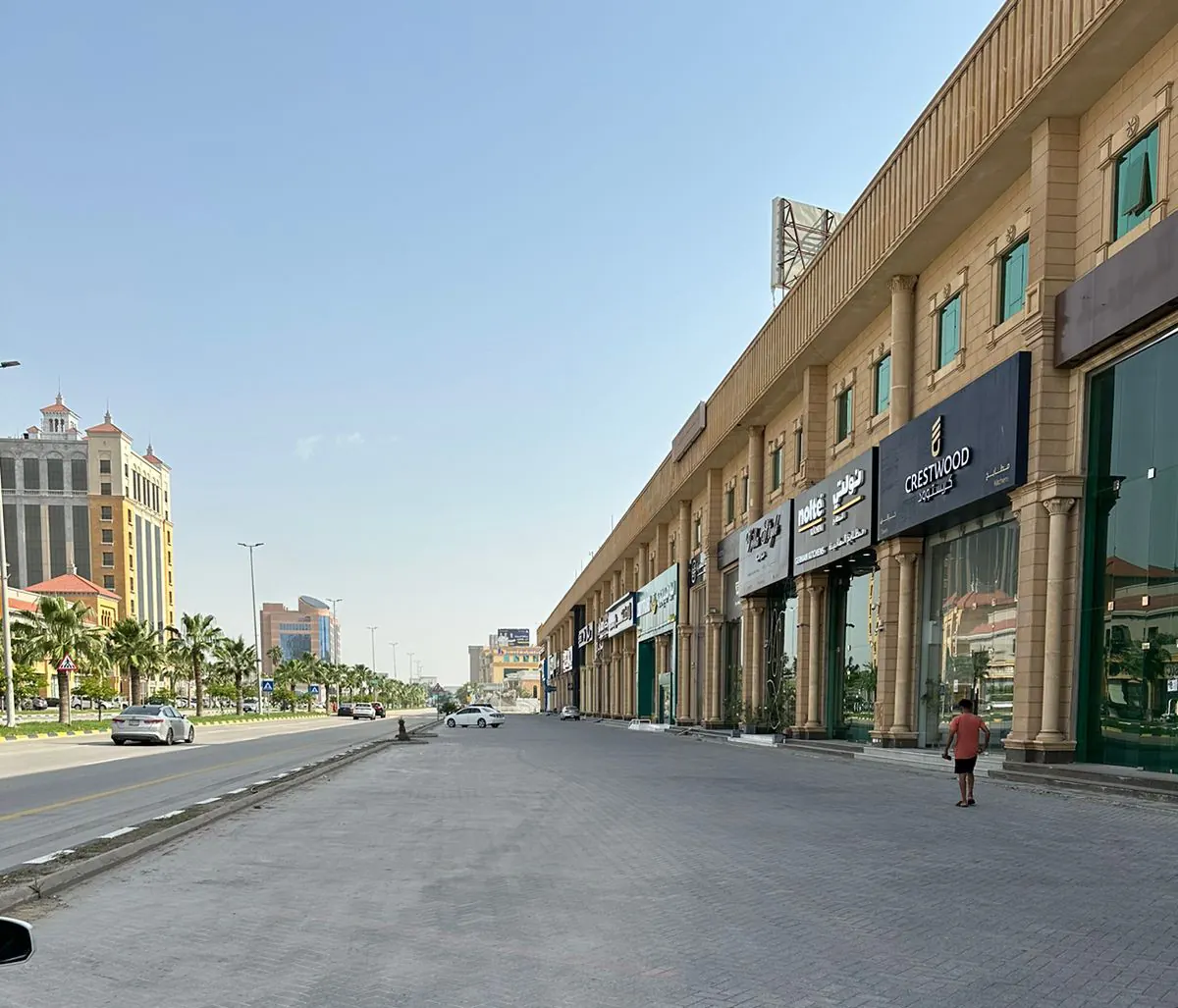 واجهة المعارض على امتداد الرصيف، تتتابع لافتاتها وأعمدتها الحجرية نحو الطريق.