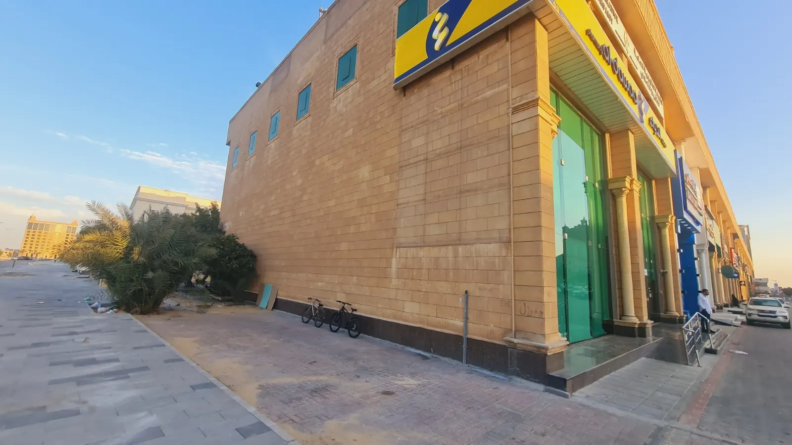 الجدار الجانبي للمجمع بالحجر الرملي، مع واجهة أول معرض الزجاجية الخضراء عند الزاوية.