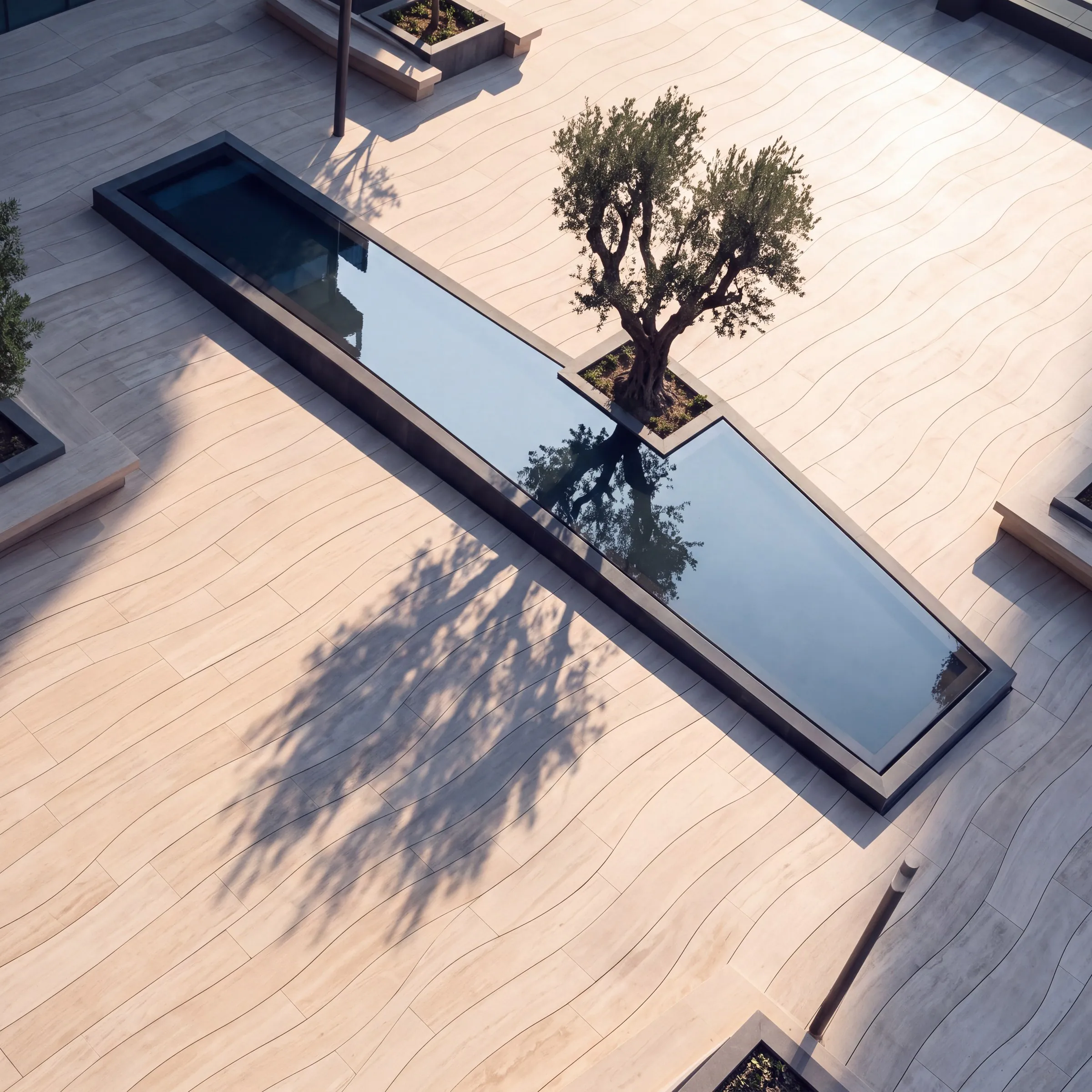 A tree casting its shadow across the stone deck beside a narrow water channel.